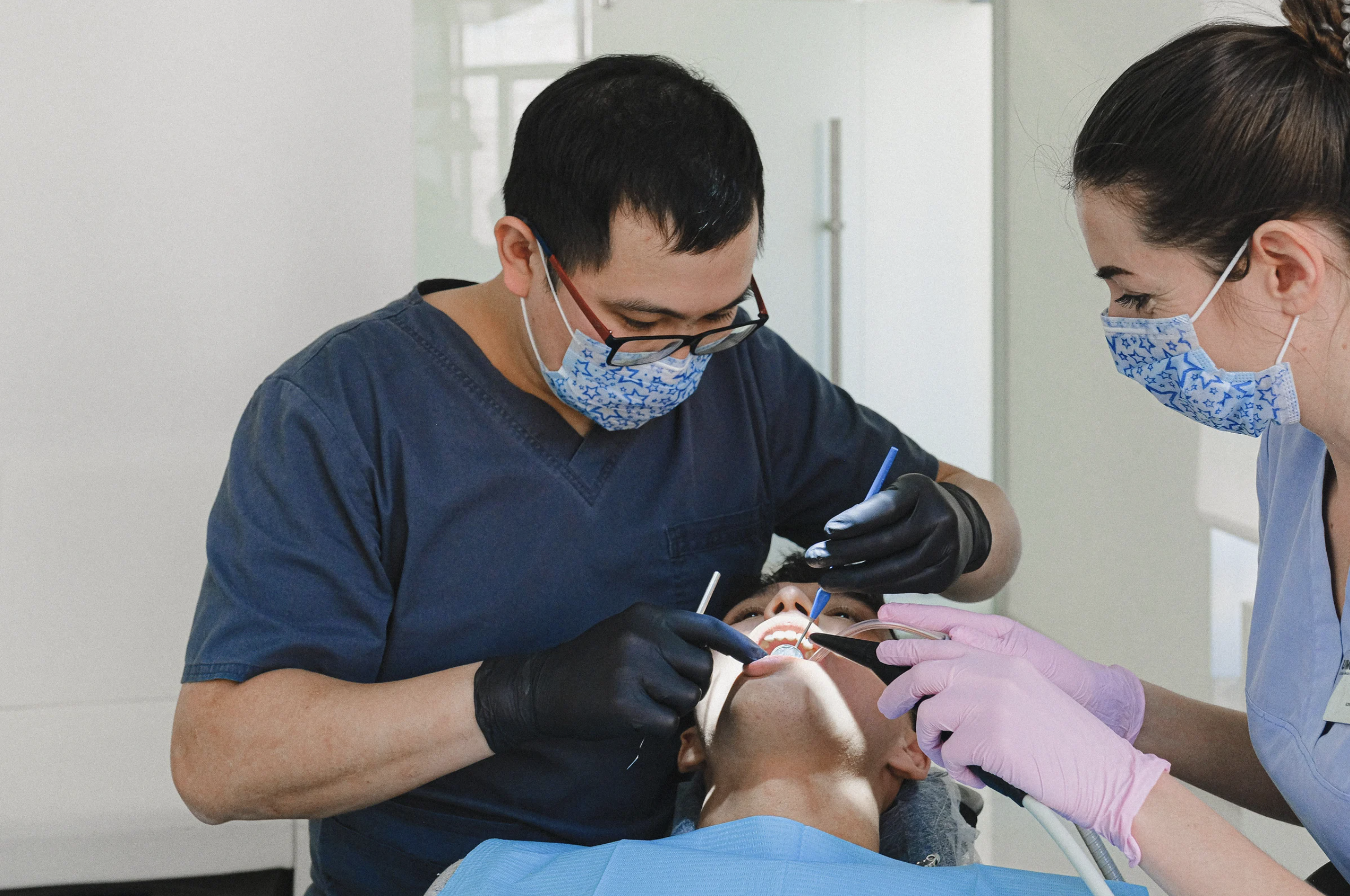 A dentist and dental assistant performing scaling and root planing for a patient.